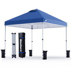 A blue pop-up canopy tent with white support poles, shown fully assembled on a white background. To the left, the tent is folded and standing next to its black carrying bag, which has the brand name 'Nashura' printed vertically in white with blue accents.