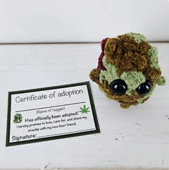 Crocheted hedgehog toy with a 'Certificate of adoption' on a white background
